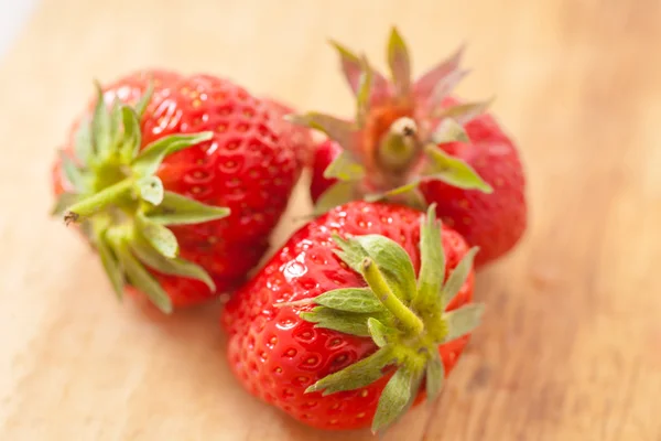 Three strawberries on wooden table — Stock Photo, Image