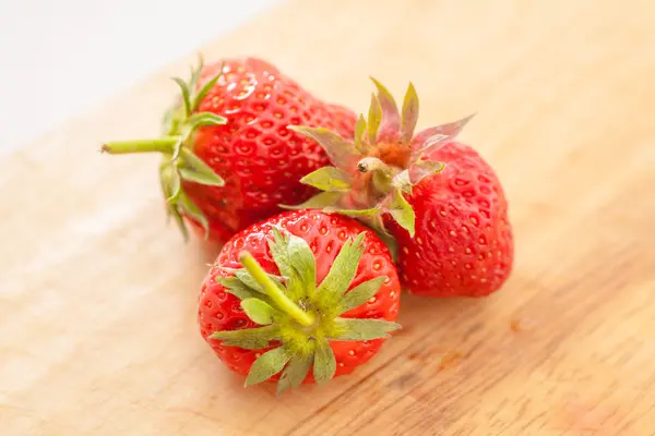 Three strawberries on wooden table — Stock Photo, Image