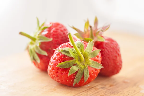 Three strawberries on wooden table — Stock Photo, Image