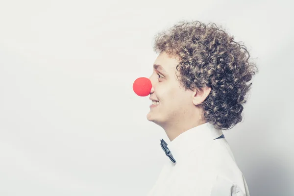Unga studen eller affärsman med en röd clown näsa. Studio skott. huvud och axlar. — Stockfoto