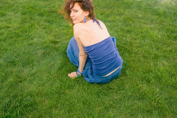 Rudy kobiet siedzi na zielonej trawie — Zdjęcie stockowe