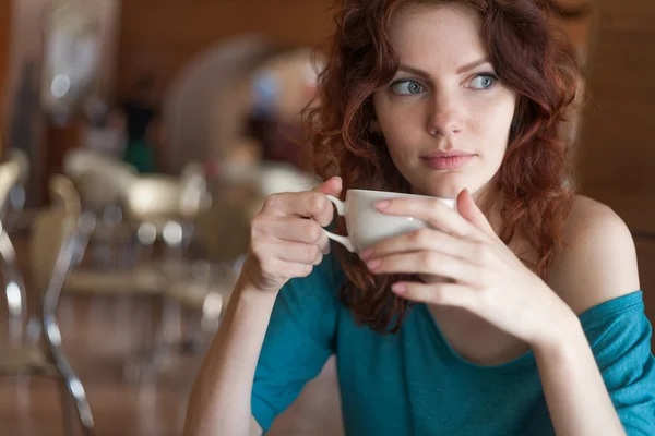 赤毛の女性と、cafee に座って一杯のコーヒーを保持 — ストック写真