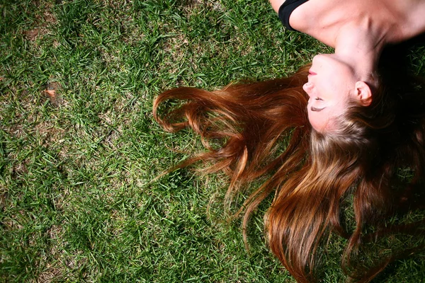 Jonge vrouw met lang blond haar liggen op het gras slapen of denken. — Stockfoto