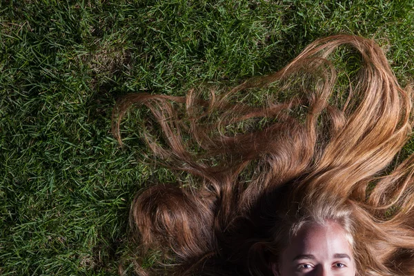 Beautiful young girl is lying on green grass — Stock Photo, Image