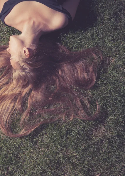 Beautiful young girl is lying on green grass — Stockfoto