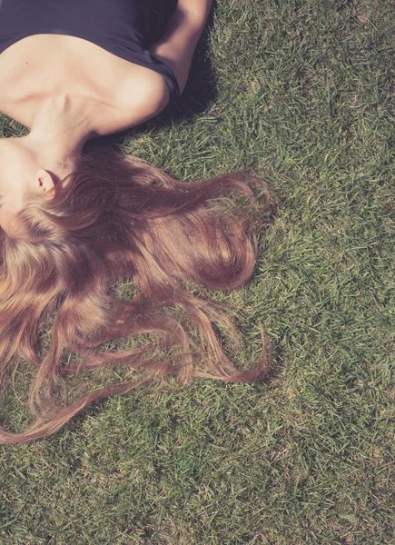 Bonito jovem mulher deitada no campo de grama na noite do parque — Fotografia de Stock