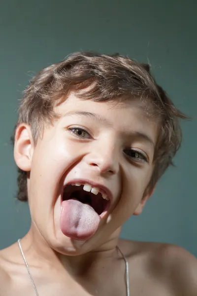 Liten pojke stående sticker ut tungan — Stockfoto
