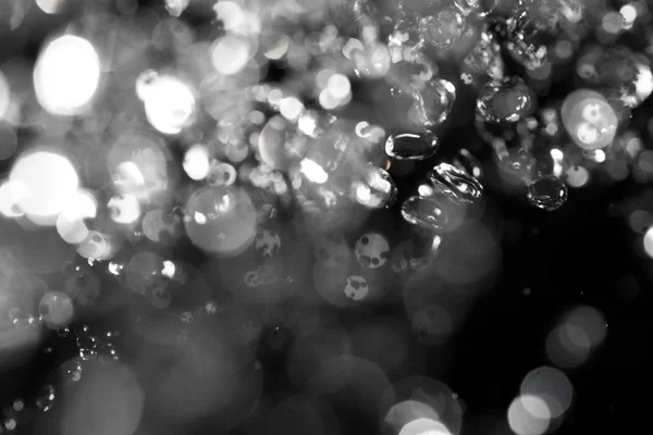 Luces Bokeh sobre fondo negro, plano de gotas voladoras de agua en el aire — Foto de Stock