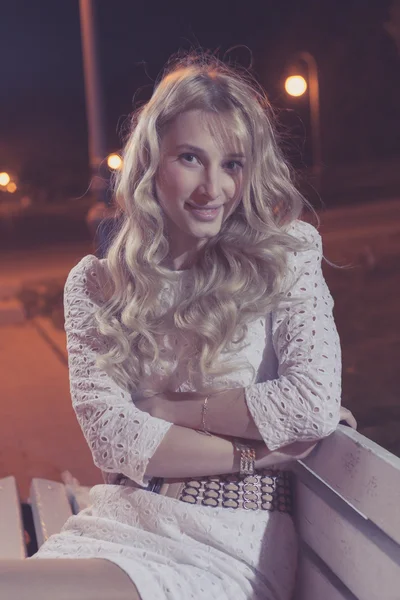 Блондинка на скамейке по ночам в тонировке — стоковое фото