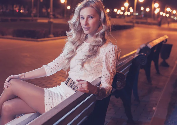 Блондинка на скамейке по ночам — стоковое фото