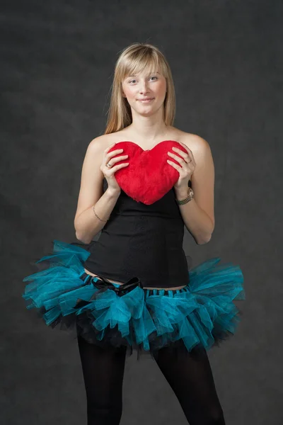 Bella giovane donna con un cuscino rosso a forma di cuore e sorridente — Foto Stock