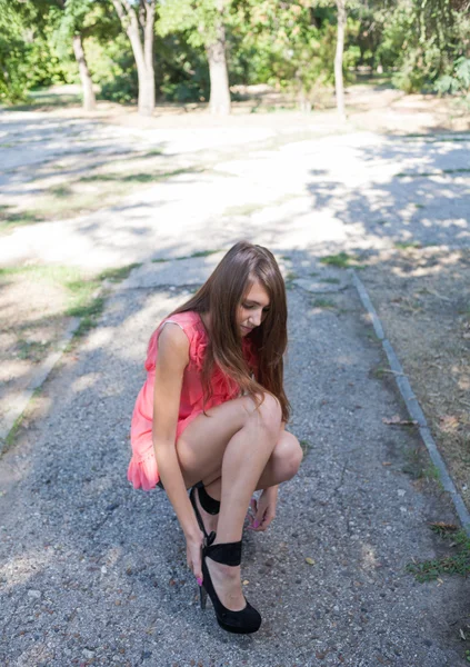 Delgada, hermosa mujer joven en vestido rosa de pie en el parque verde — Foto de Stock