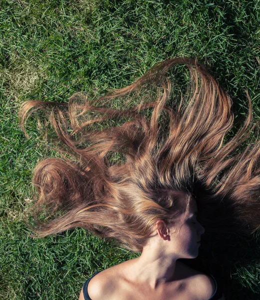 Beautiful young girl is lying on green grass — Stock Photo, Image