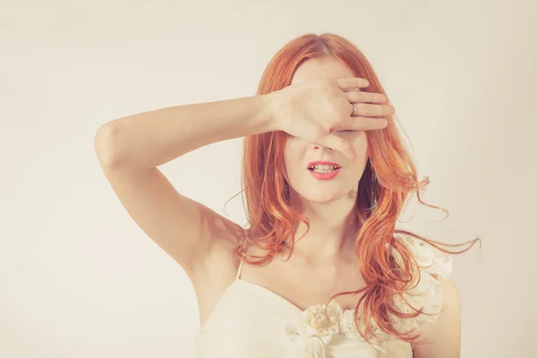 Giovane donna rossa, ragazza che copre i suoi occhi su sfondo bianco . — Foto Stock