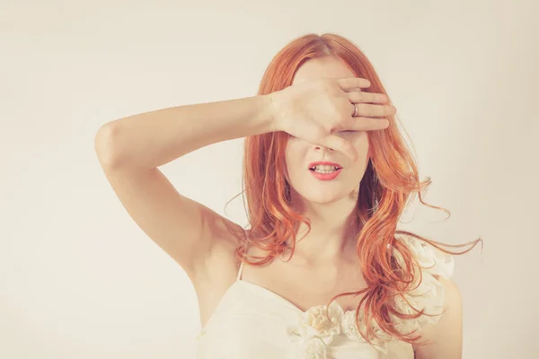 Jonge redhead vrouw, meisje die betrekking hebben op haar ogen op witte achtergrond. — Stockfoto