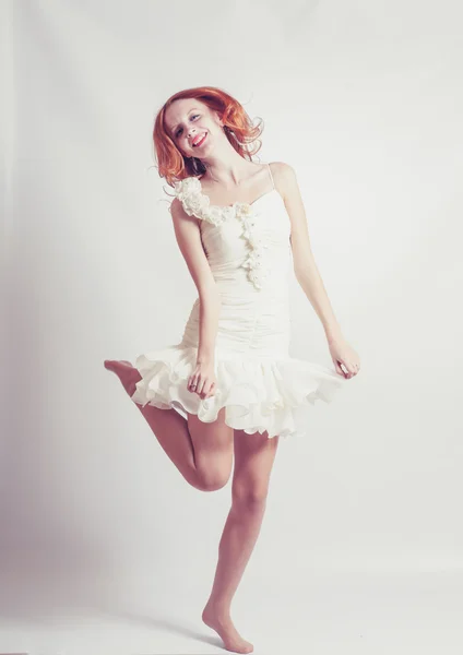 Jonge vrouw in witte jurk, springt. op grijze achtergrond. — Stockfoto