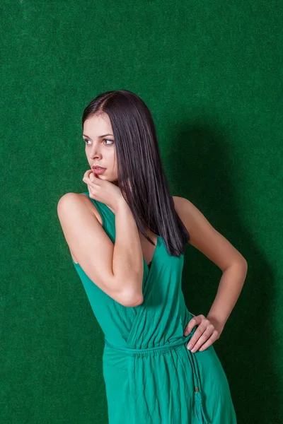 Morena em vestido verde contra a parede — Fotografia de Stock