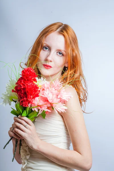 Redhead with bunch of flowers in studio on white — Stock Photo, Image