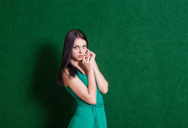 Brunette in green dress against wall — Stock Photo, Image