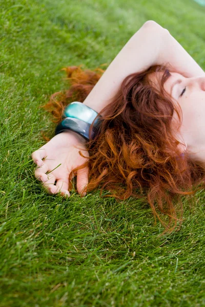 Ruiva menina escorregando na grama verde — Fotografia de Stock