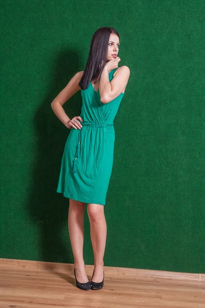 Brunette en robe verte posant contre le mur vert — Photo