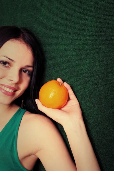 Kvinna med en orange i hennes händer — Stockfoto