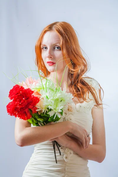 Pelirroja con ramo de flores en estudio sobre blanco — Foto de Stock