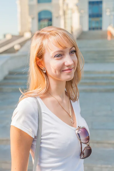 Blond 20s female in city park against building — Stock Photo, Image