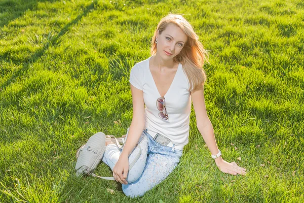 新鲜的草地上坐着的金发碧眼女人 — 图库照片