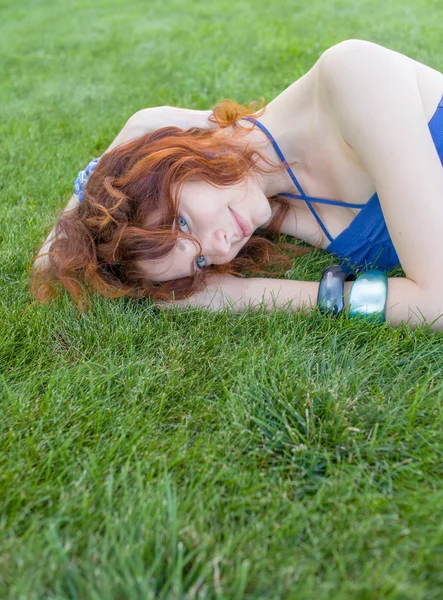 Krásná rusovláska dívka leží na zelené trávě — Stock fotografie
