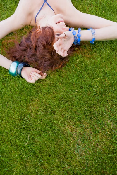 Улыбающаяся рыжая девушка на зеленой траве — стоковое фото