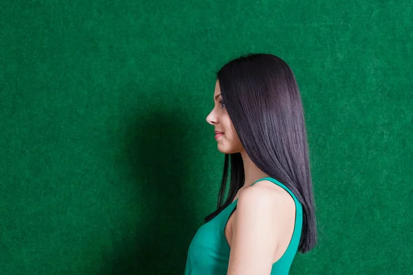 Brunette in green dress against wall — Stock Photo, Image