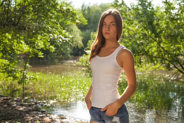 Beautiful young blonde woman in white tank top and denim shorts laughing out loud (LOL) outdoors — Stock Photo, Image