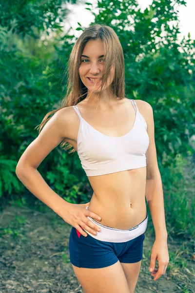 Mulher loira jovem bonita em top tanque branco e calções jeans rindo alto (LOL) ao ar livre — Fotografia de Stock
