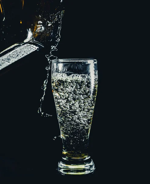 Glass pouring drink on black — Stock Photo, Image