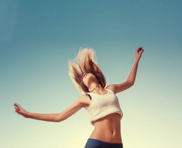 Blond tonåring flicka hoppande nöjd med den blå himlen i ryggen — Stockfoto