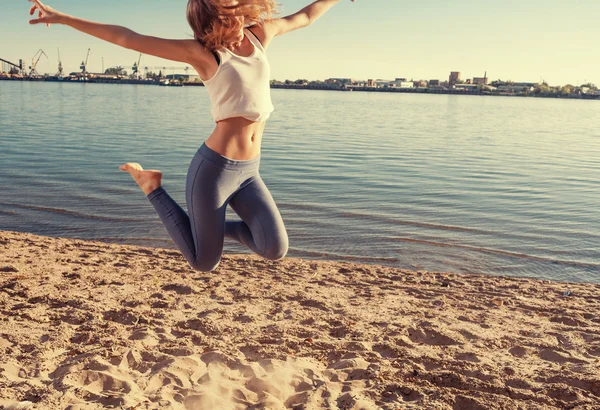 Menina feliz pulando na praia — Fotografia de Stock