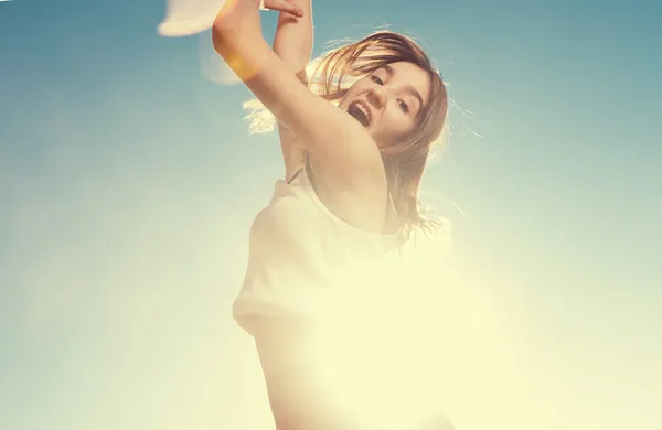 Vrolijke vrouw springen met de blauwe lucht op de achtergrond — Stockfoto