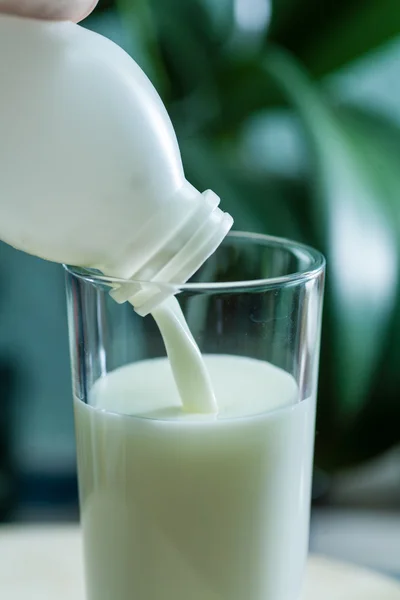 Milk poured in glass cup over indoors background — Stock Photo, Image