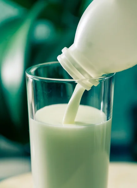 Milk poured in glass cup over indoors background — Stock Photo, Image