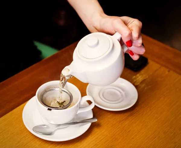 Mulher derramando chá na xícara — Fotografia de Stock