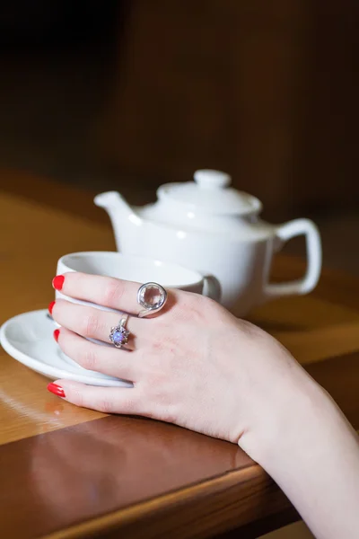 Bule, xícara de chá e mão de mulheres na mesa — Fotografia de Stock