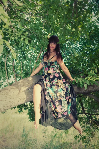 Bir yeşil ağaç üzerinde oturan kadın — Stok fotoğraf