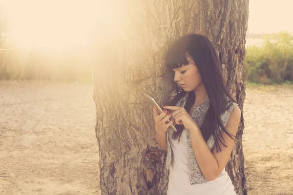 Brunette using tablet computer near tree — Stock Photo, Image