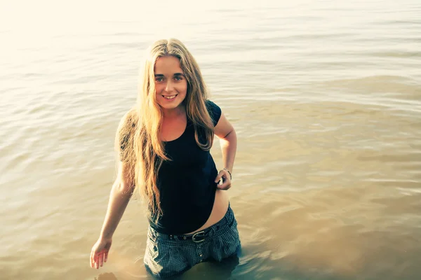 Blonde aux cheveux longs souriant dans l'eau à l'extérieur — Photo