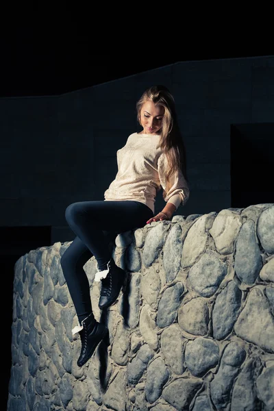 石の壁の上に座ってスポーツ ・ ウェアでかわいい女の子 — ストック写真