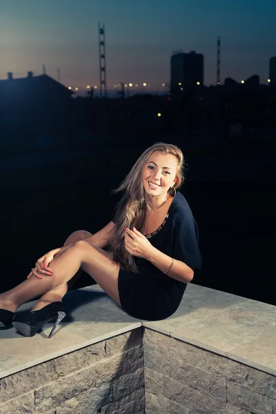 Blondine sitzt nachts auf Brüstung — Stockfoto
