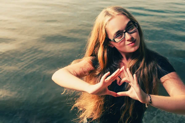 Jonge blonde makinf hart vorm door haar handen — Stockfoto