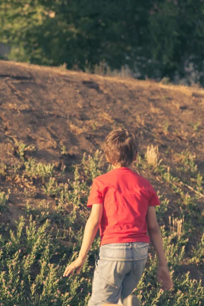 Мальчик в красной футболке смотрит на склон — стоковое фото