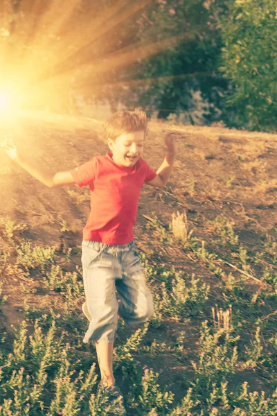 Мальчик веселится летом. Бегущий по склону в лучах солнца — стоковое фото
